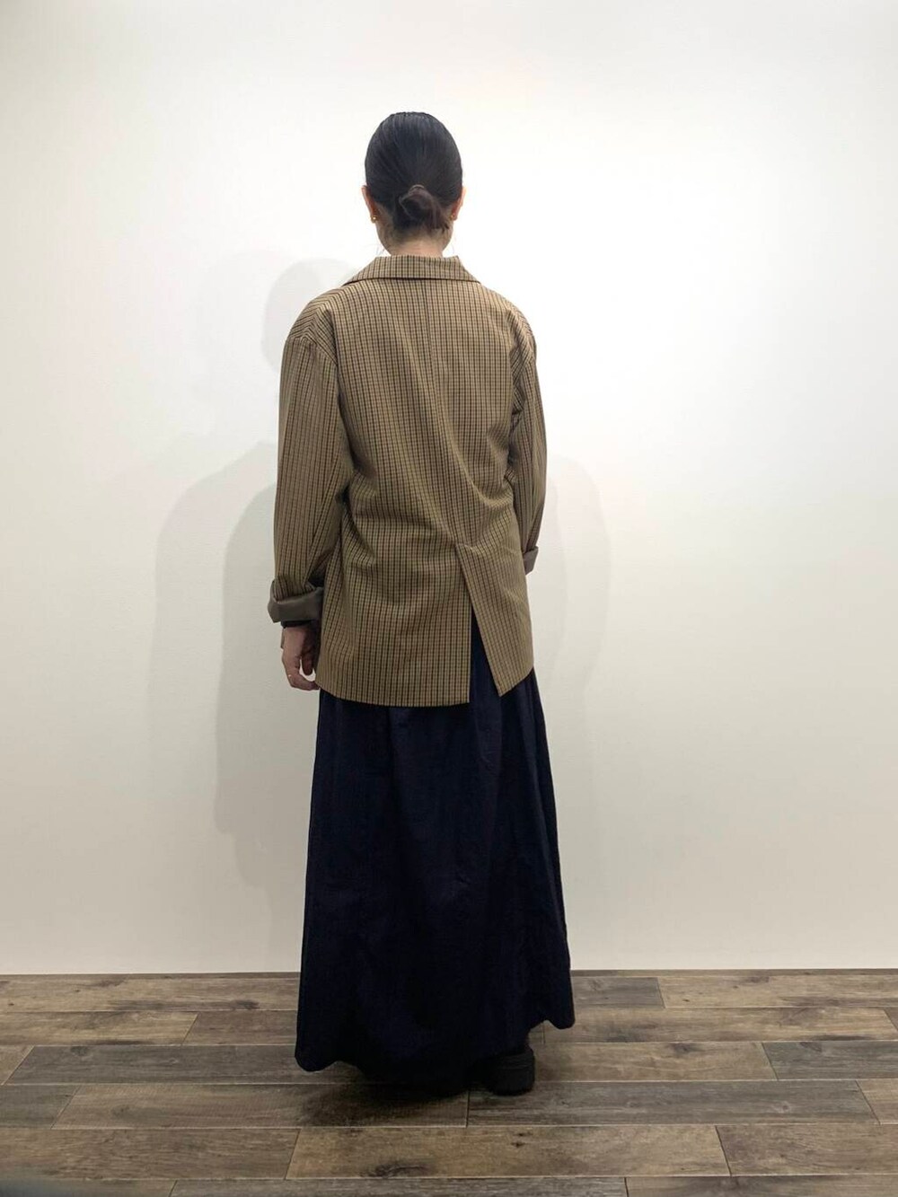 ブラック系のブーツ、ブルー系のスカート、ブラウン系のテーラードジャケットを着用したレディースの秋コーディネートの5枚目の写真