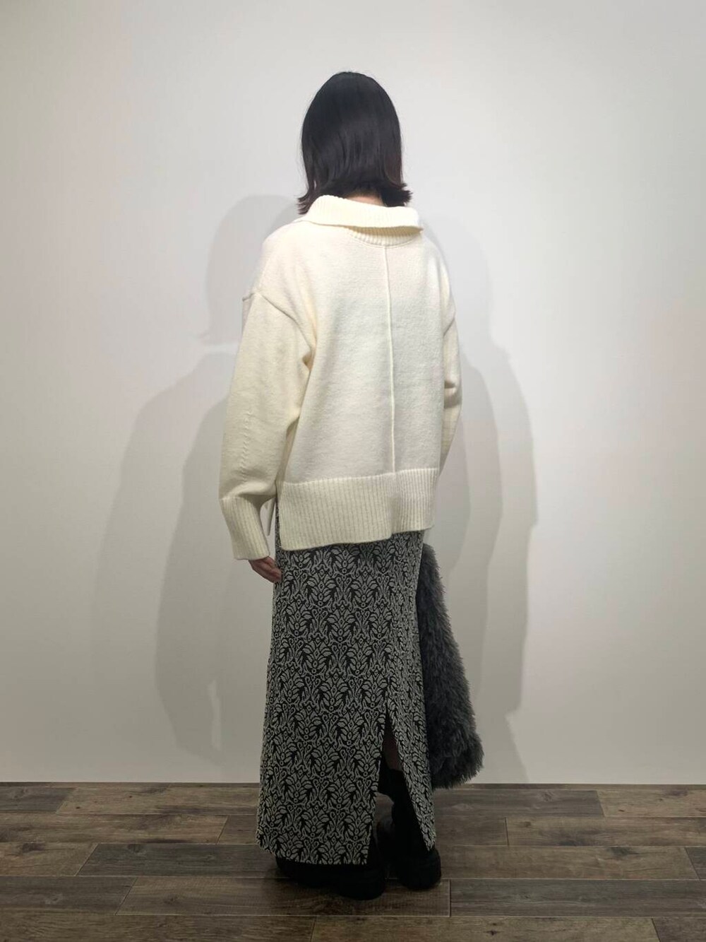 ブラック系のブーツ、グレー系のトートバッグ、ホワイト系のニット/セーターを着用したレディースの秋コーディネートの5枚目の写真