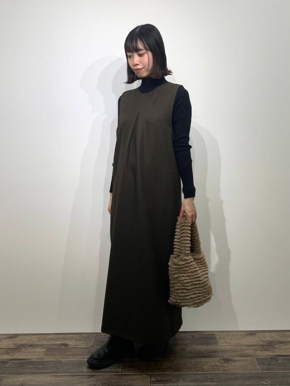 ブラック系のニット/セーター、イエロー系のトートバッグ、ブラウン系のワンピースを着用したレディースの秋コーディネートの4枚目の写真