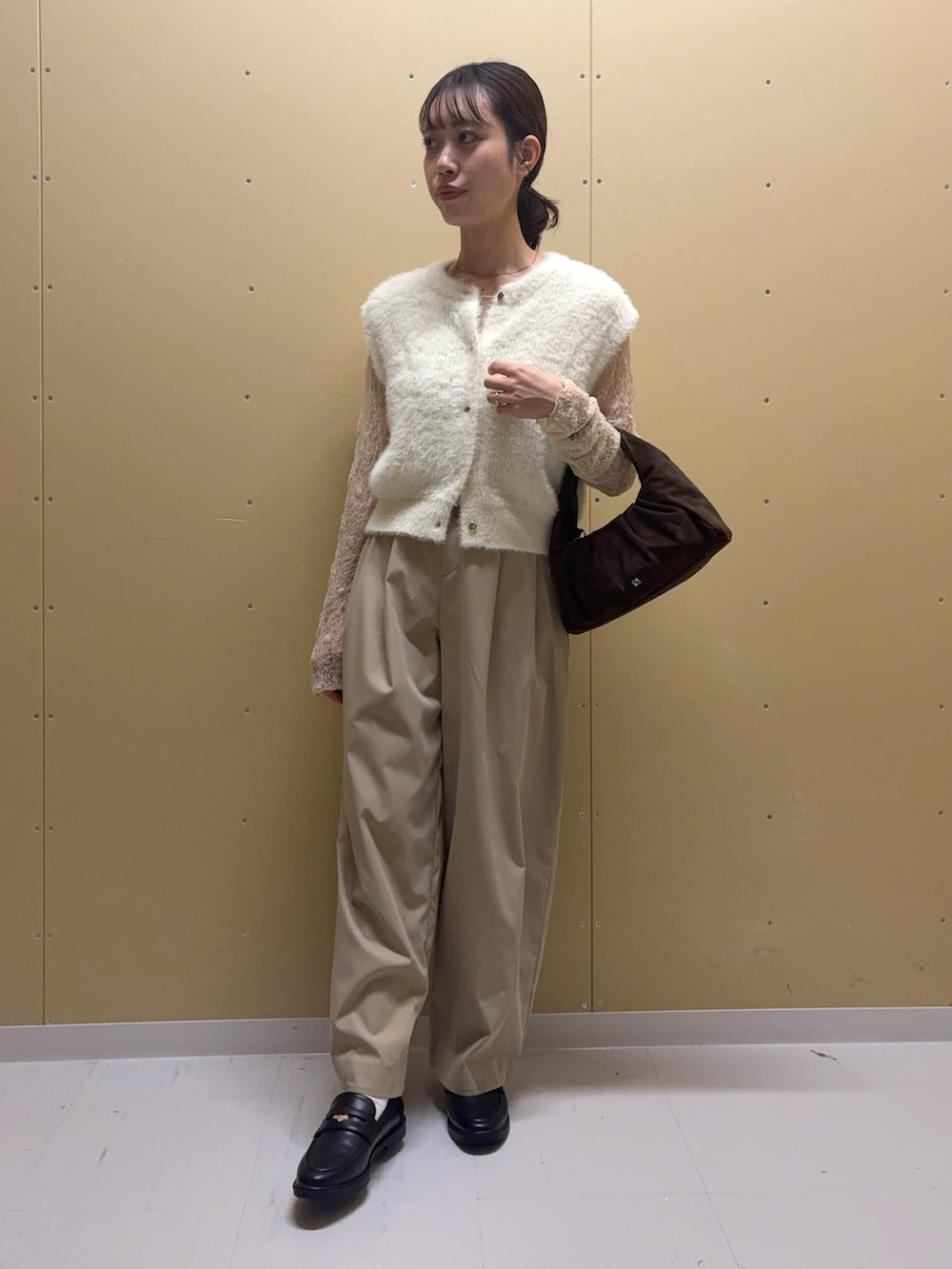 ホワイト系のニット/セーター、ベージュ系のTシャツ/カットソー、ブラウン系のハンドバッグを着用したレディースの秋コーディネートの3枚目の写真