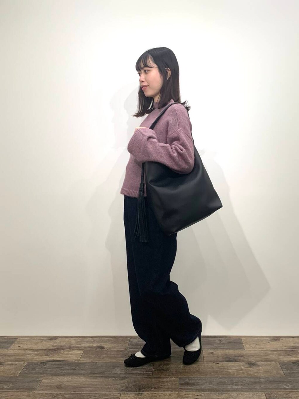 ブラック系のブーツ、ブルー系のデニムパンツ、ブラック系のトートバッグを着用したレディースの秋コーディネートの5枚目の写真