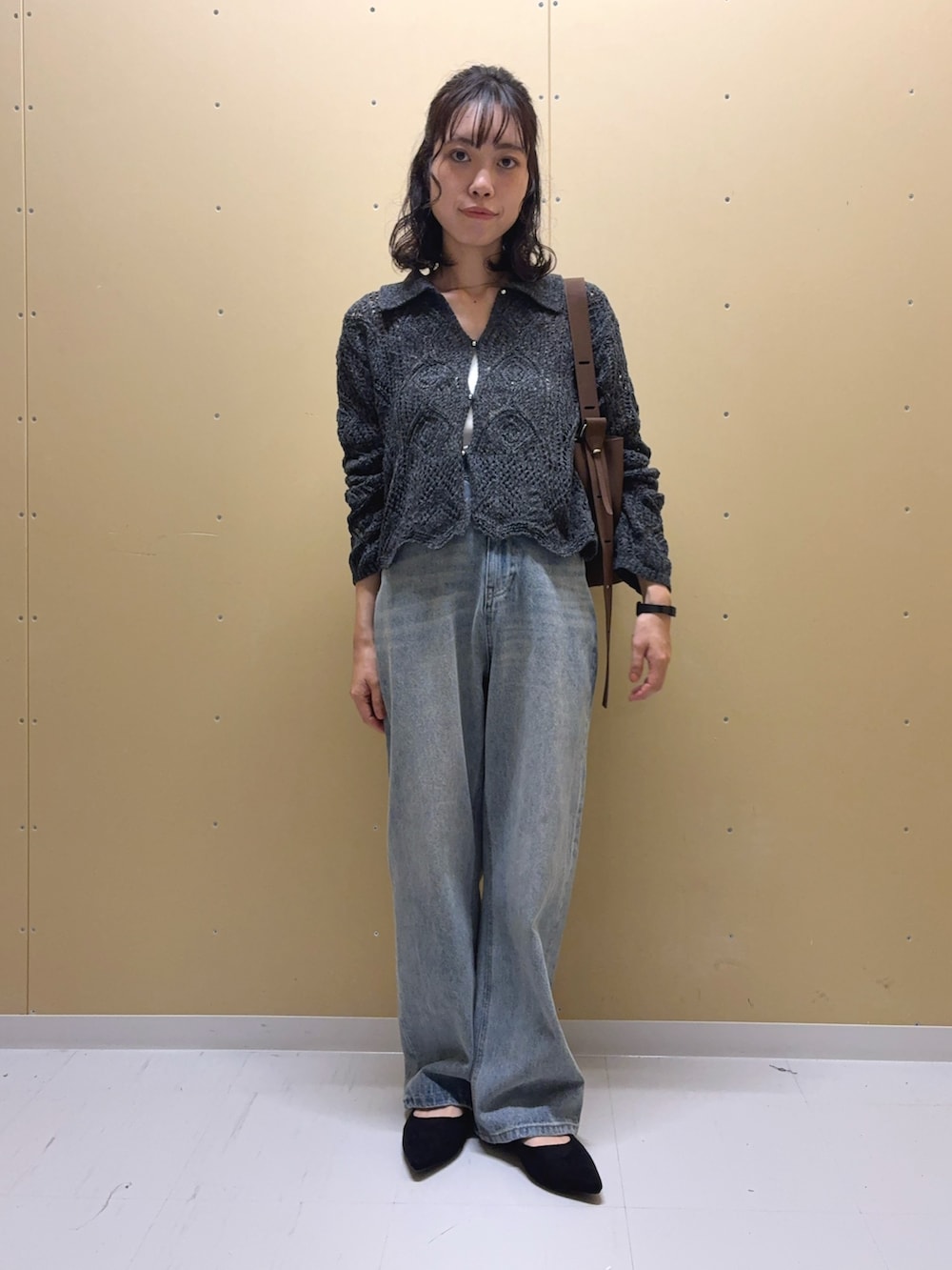 ブルー系のデニムパンツ、グレー系のカーディガン/ボレロ、ブラウン系のショルダーバッグを着用したレディースの秋コーディネートの2枚目の写真