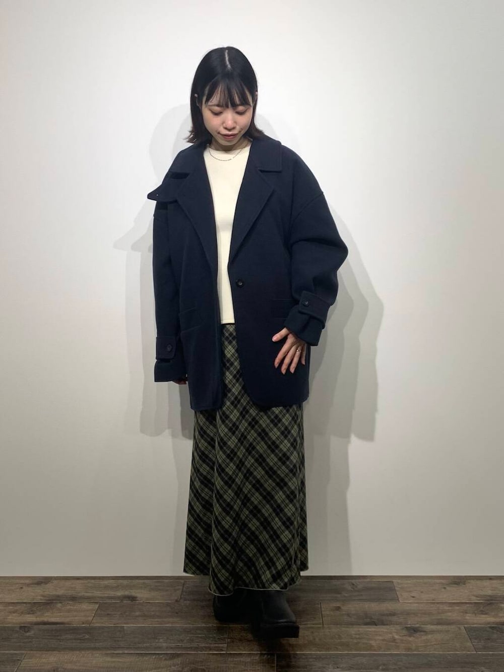 ブルー系のステンカラーコート、ブラック系のブーツ、ホワイト系のTシャツ/カットソーを着用したレディースの秋コーディネートの3枚目の写真