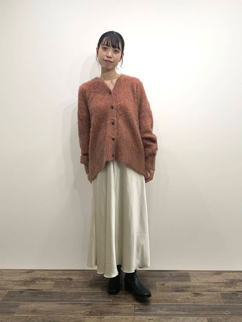 ブラック系のブーツ、ホワイト系のスカート、オレンジ系のカーディガン/ボレロを着用したレディースの秋コーディネートの2枚目の写真