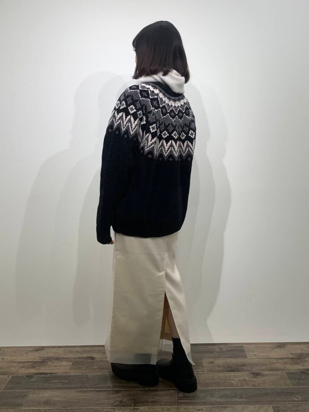 ブラック系のニット/セーター、ブラック系のブーツ、ホワイト系のスカートを着用したレディースの冬コーディネートの5枚目の写真