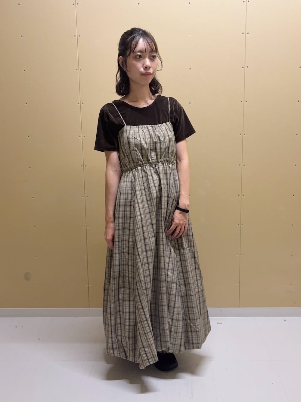 ベージュ系のワンピース、ブラウン系のTシャツ/カットソー、ブラック系のスニーカーを着用したレディースの夏コーディネートの2枚目の写真