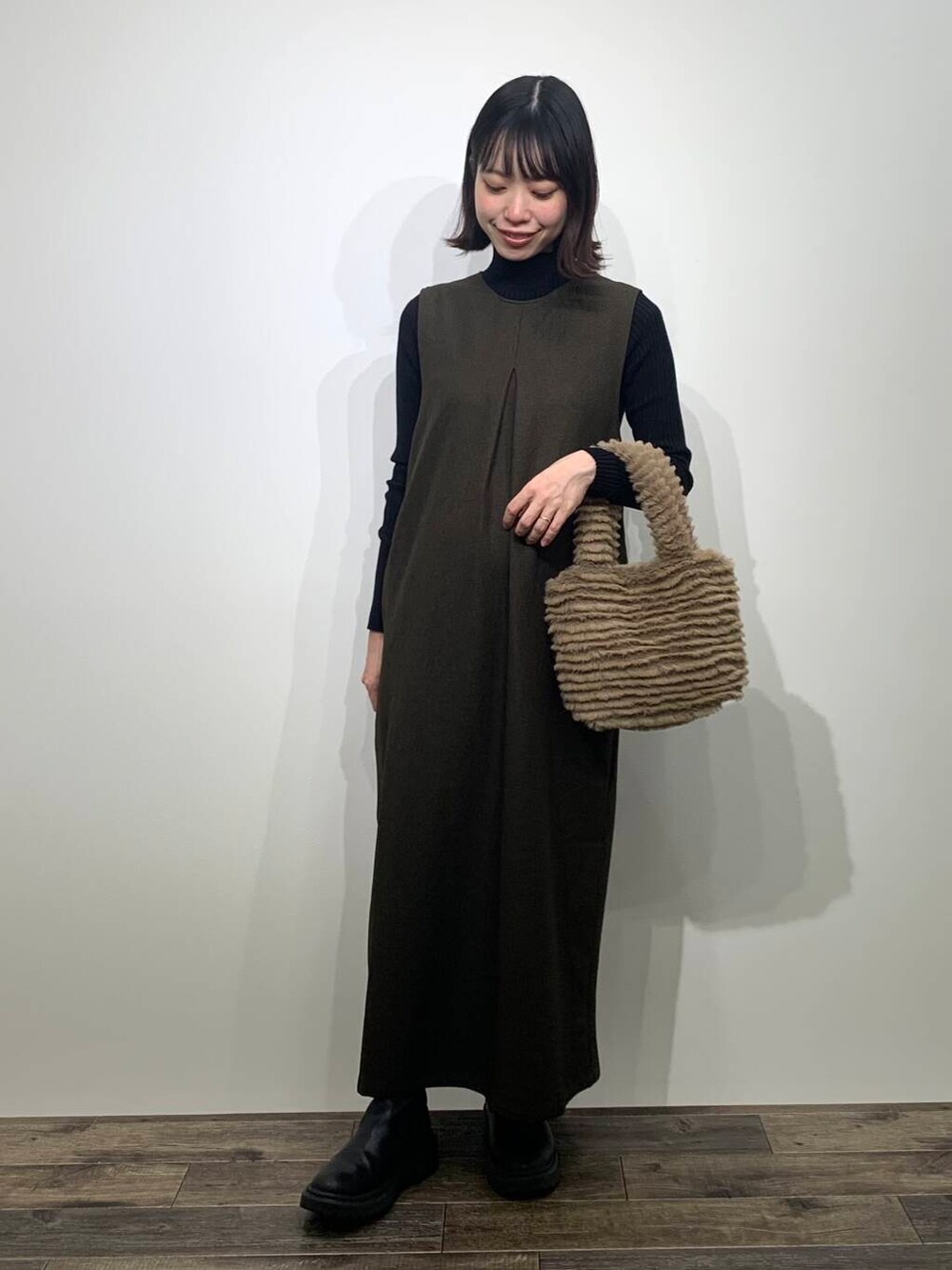 ブラック系のニット/セーター、イエロー系のトートバッグ、ブラウン系のワンピースを着用したレディースの秋コーディネートの2枚目の写真