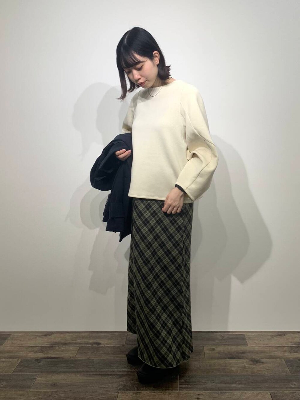 ブルー系のステンカラーコート、ブラック系のブーツ、ホワイト系のTシャツ/カットソーを着用したレディースの秋コーディネートの7枚目の写真