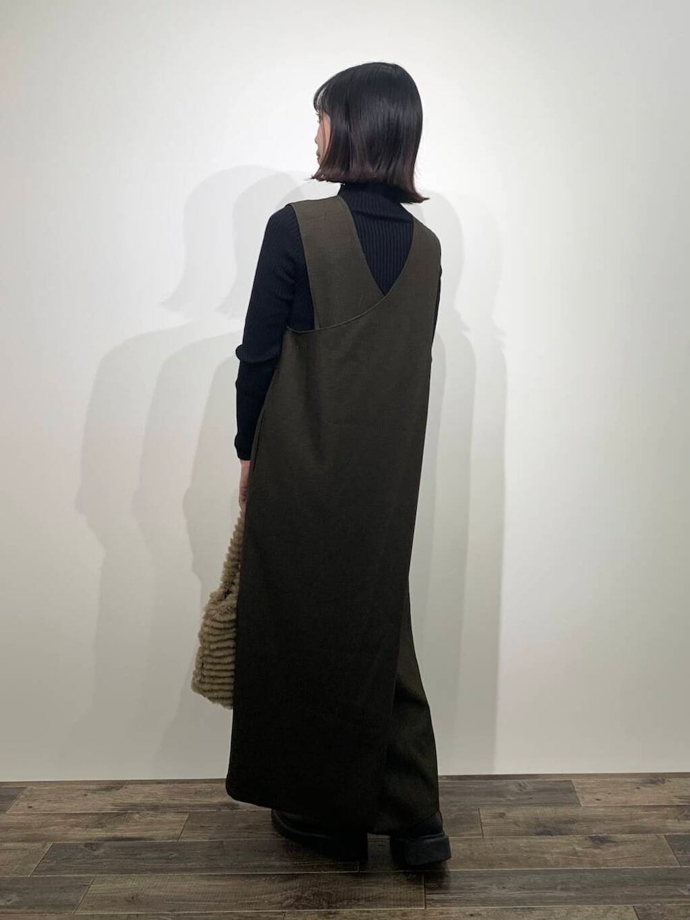 ブラック系のニット/セーター、イエロー系のトートバッグ、ブラウン系のワンピースを着用したレディースの秋コーディネートの5枚目の写真