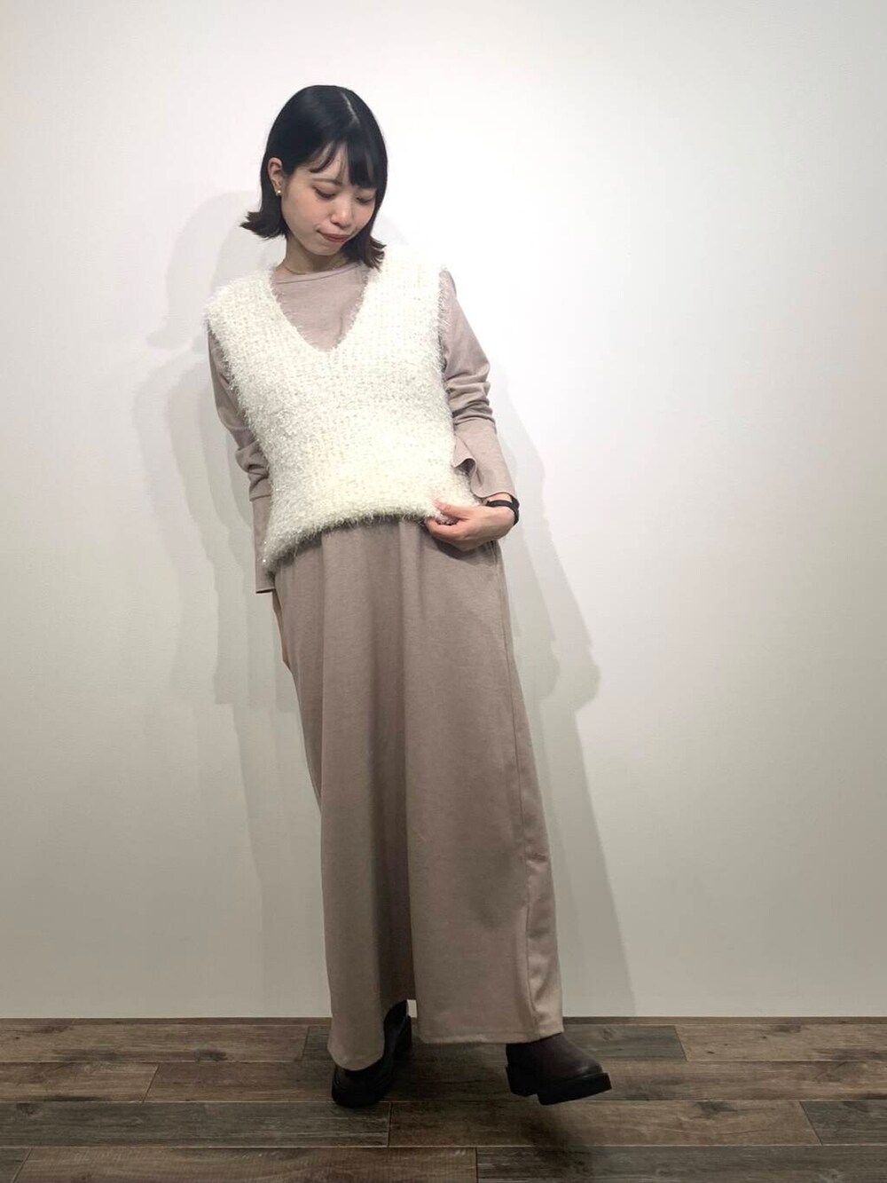 ベージュ系のトートバッグ、ブラウン系のブーツ、ホワイト系のベストを着用したレディースの秋コーディネートの3枚目の写真