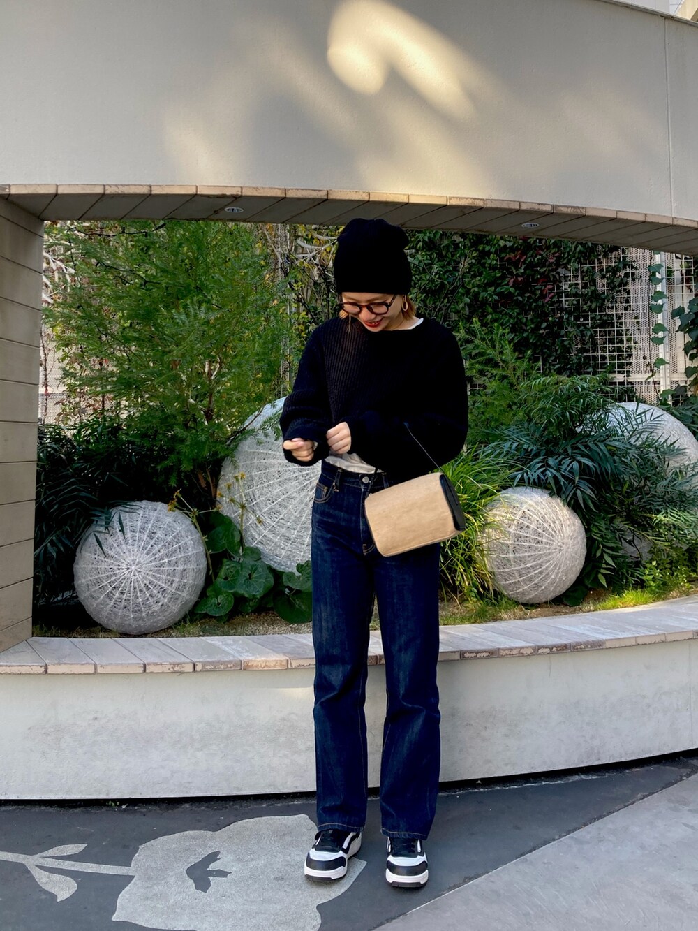 ブラック系のワンピース、ブルー系のデニムパンツ、ブラウン系のメガネを着用したレディースの冬コーディネートの2枚目の写真