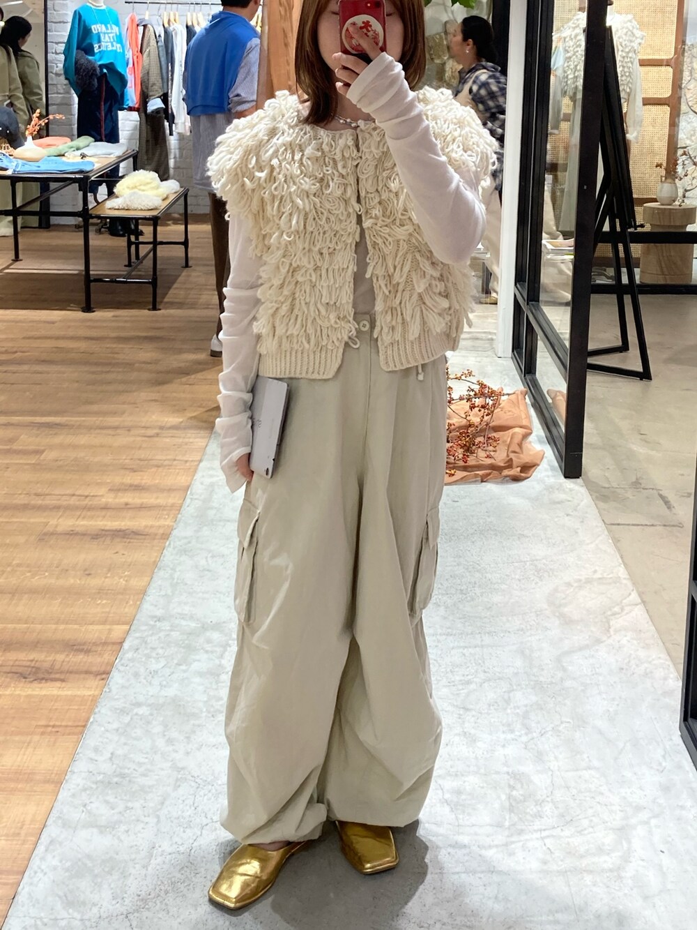 ホワイト系のベスト、ホワイト系のカーゴパンツ、ゴールド系のローファーを着用したレディースの春コーディネートの2枚目の写真