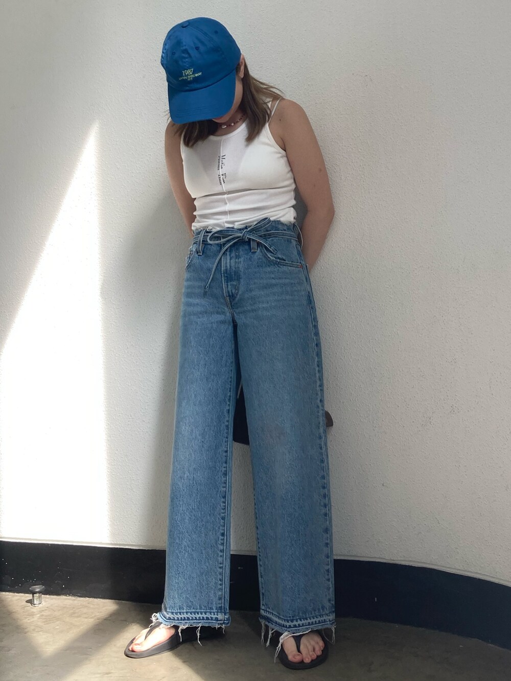 ブルー系のデニムパンツ、ブラウン系のハンドバッグ、ブルー系のキャップを着用したレディースの秋コーディネートの2枚目の写真