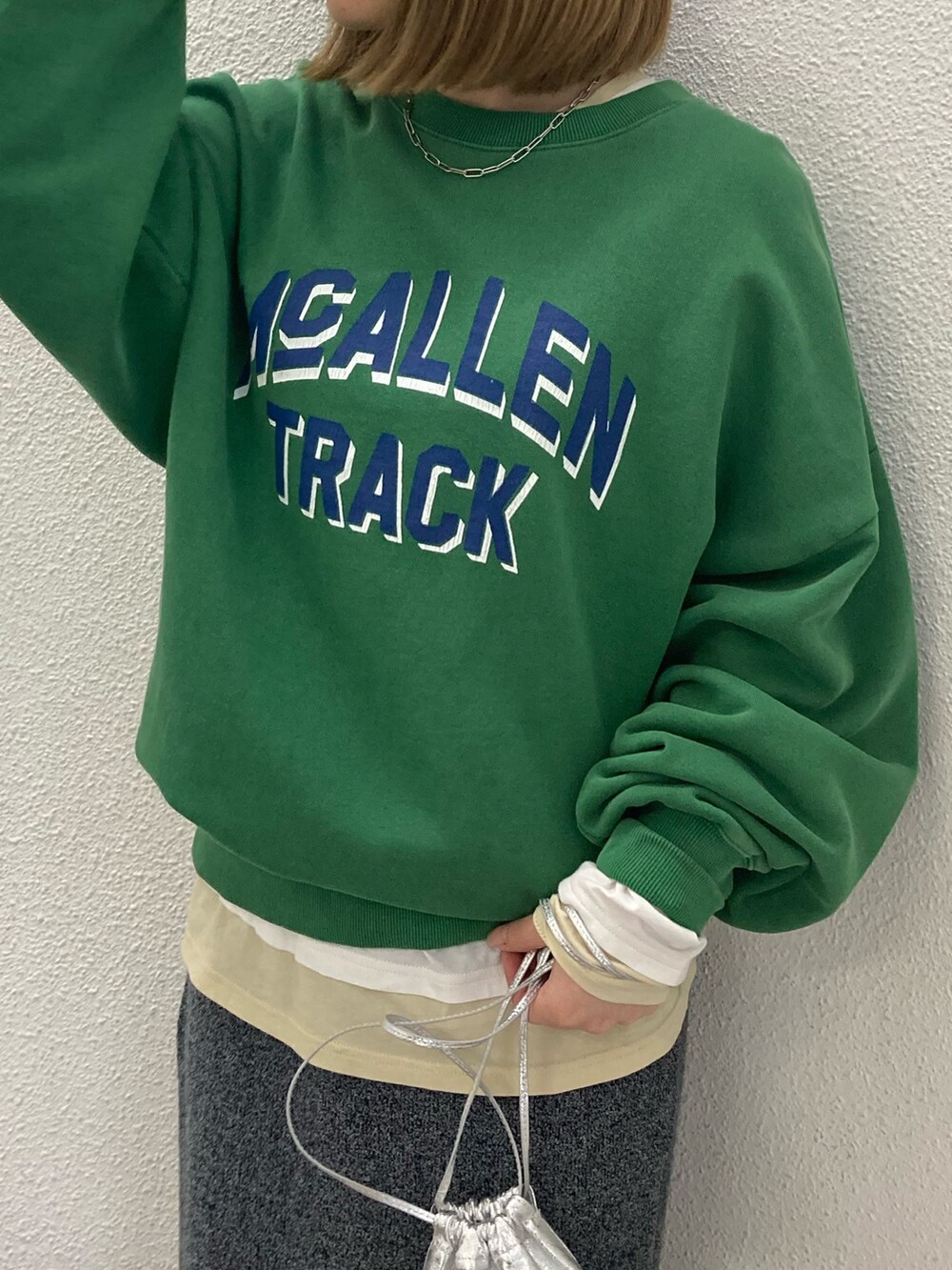 グレー系のスカート、グリーン系のスウェット、ホワイト系のTシャツ/カットソーを着用したレディースの冬コーディネートの2枚目の写真