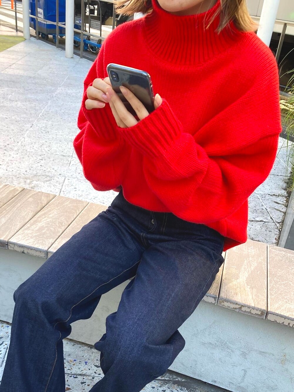 レッド系のニット/セーター、ブルー系のデニムパンツを着用したレディースの冬コーディネートの3枚目の写真