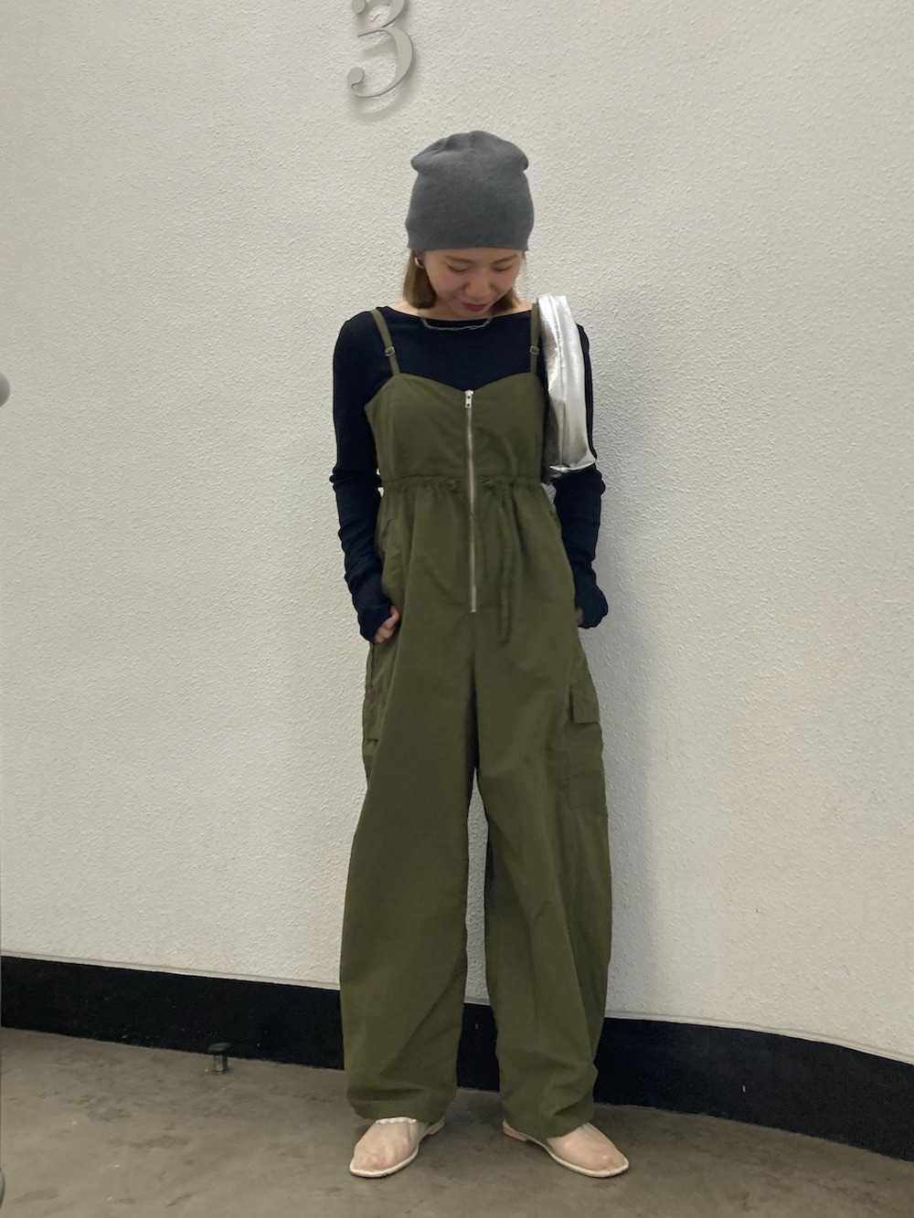 グリーン系のサロペット/オーバーオール、ブラック系のTシャツ/カットソー、シルバー系のハンドバッグを着用したレディースの冬コーディネートの2枚目の写真