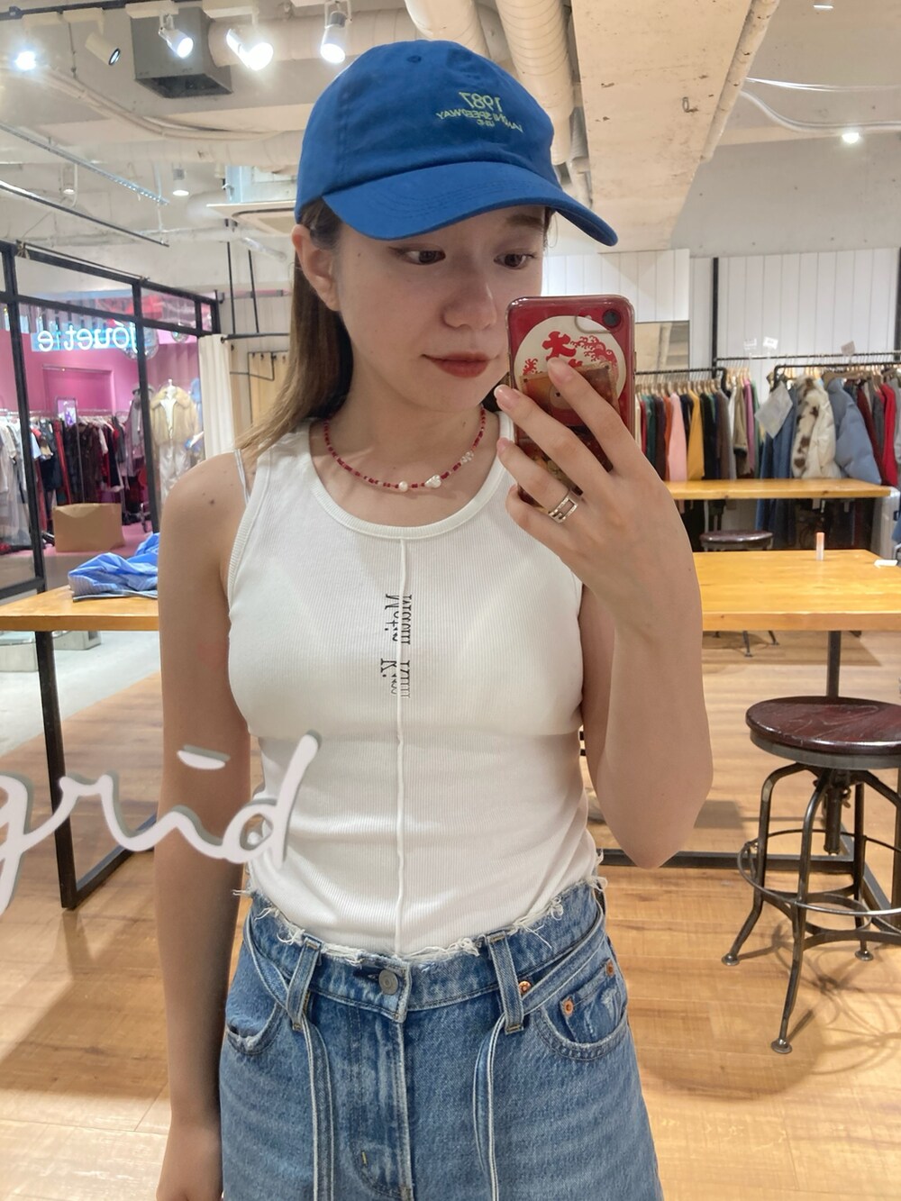 ブルー系のデニムパンツ、ブラウン系のハンドバッグ、ブルー系のキャップを着用したレディースの秋コーディネートの3枚目の写真