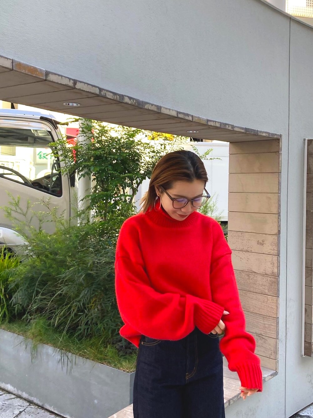 レッド系のニット/セーター、ブルー系のデニムパンツを着用したレディースの冬コーディネートの2枚目の写真