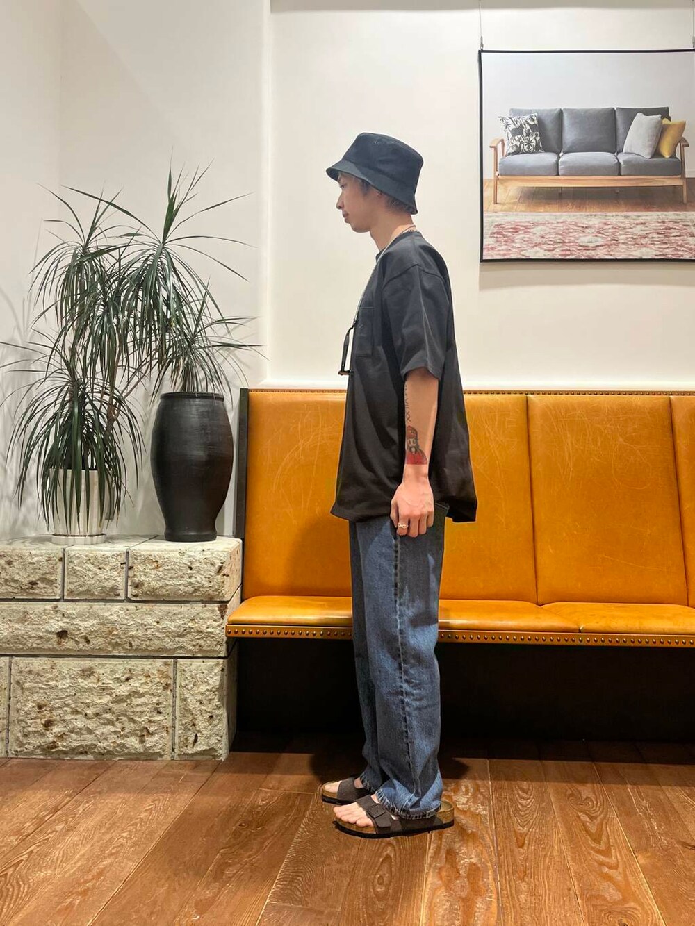 ブルー系のデニムパンツ、グレー系のサンダル、ブラック系のTシャツ/カットソーを着用したメンズの春コーディネートの2枚目の写真