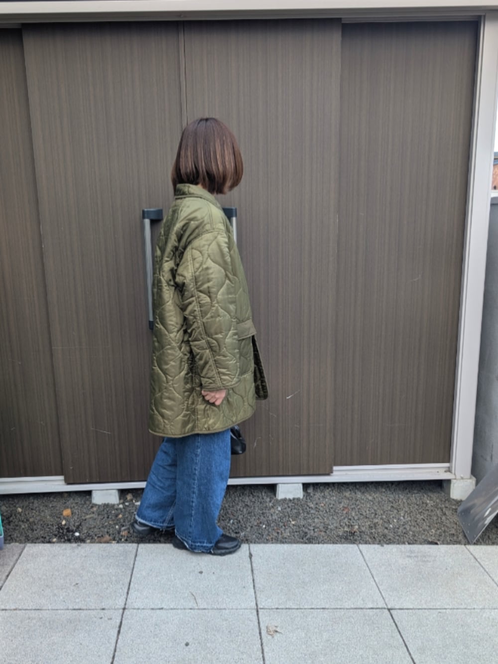 グリーン系のミリタリージャケット、ブルー系のデニムパンツ、ベージュ系のTシャツ/カットソーを着用したレディースの春コーディネートの2枚目の写真