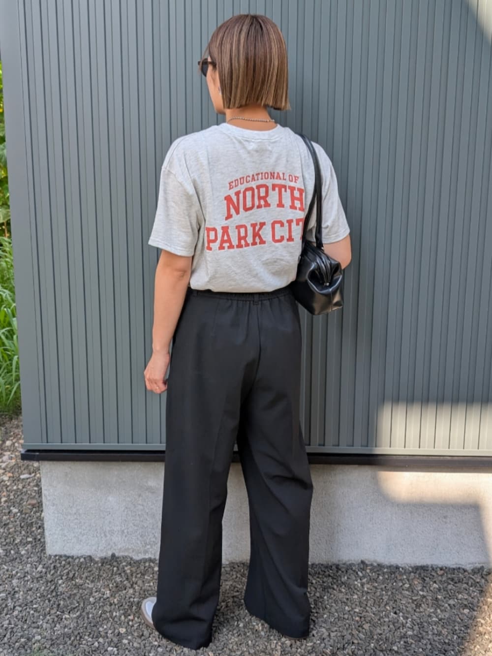 ベージュ系のTシャツ/カットソー、ブラック系のスラックス、ブラック系のトートバッグを着用したレディースの夏コーディネートの2枚目の写真