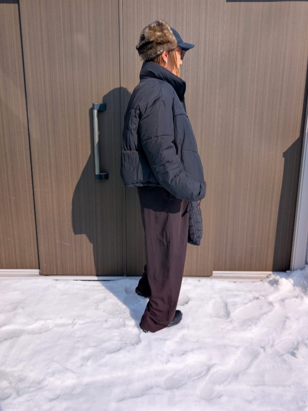 ブラック系のブルゾン、ブラウン系のパンツ、ブラック系のキャップを着用したレディースの冬コーディネートの2枚目の写真