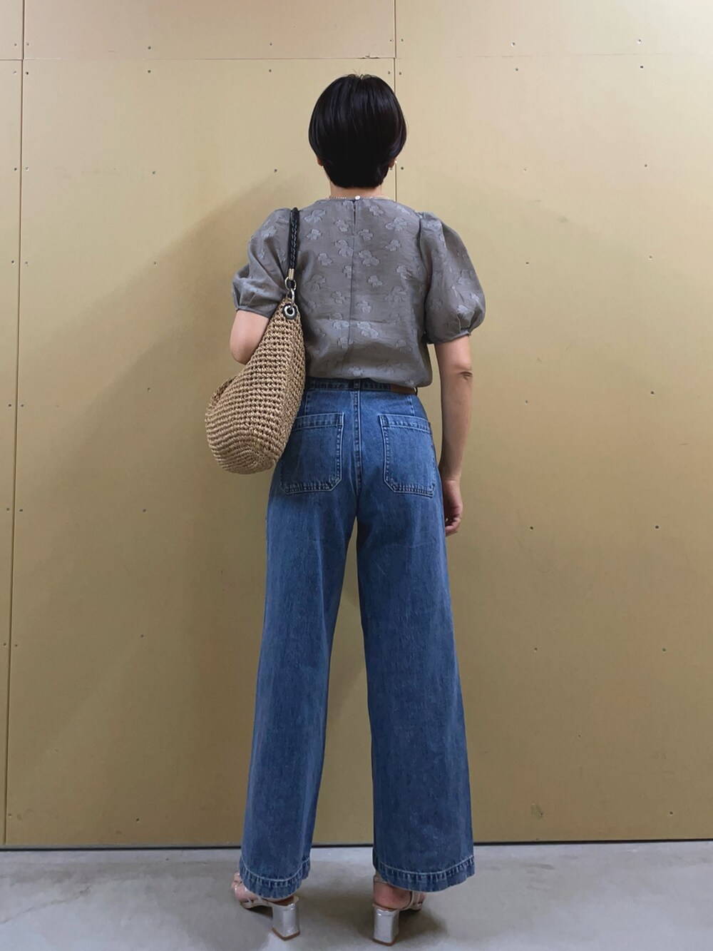 シルバー系のサンダル、ブルー系のデニムパンツ、ブラウン系のかごバッグを着用したレディースの夏コーディネートの4枚目の写真