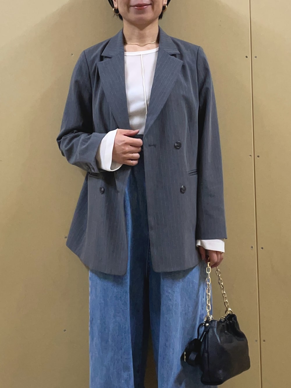 ブルー系のデニムパンツ、ホワイト系のTシャツ/カットソー、ブラック系のショルダーバッグを着用したレディースの冬コーディネートの5枚目の写真