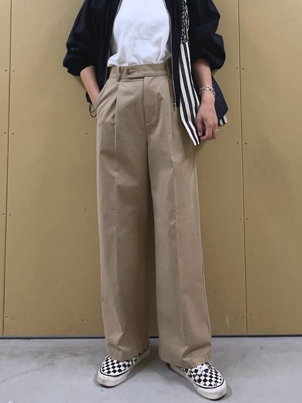 ブラック系のブルゾン、ベージュ系のチノパンツ、ブラック系のトートバッグを着用したレディースの春コーディネートの7枚目の写真