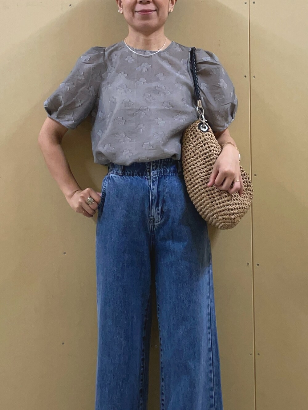 シルバー系のサンダル、ブルー系のデニムパンツ、ブラウン系のかごバッグを着用したレディースの夏コーディネートの5枚目の写真