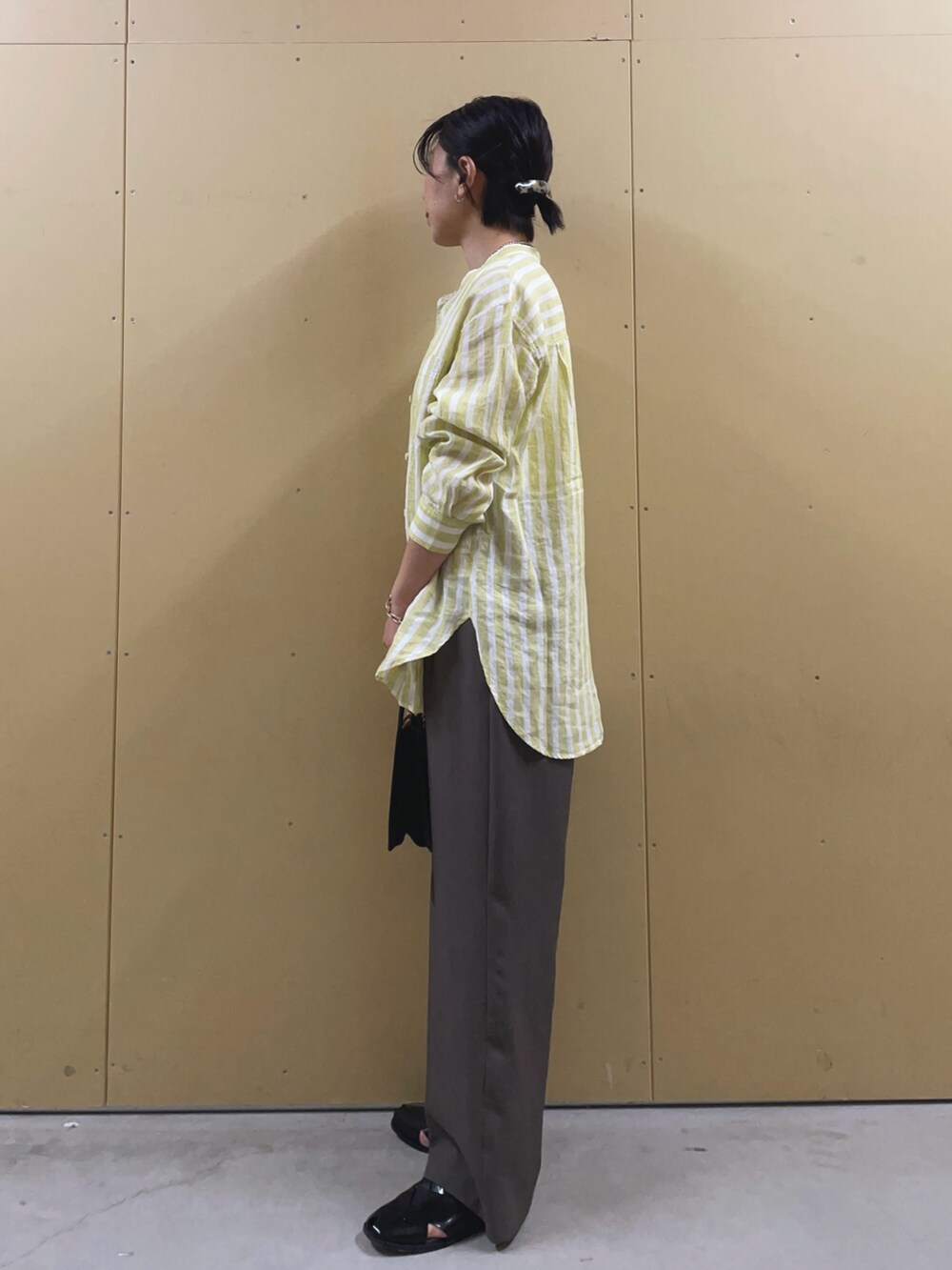 イエロー系のシャツ/ブラウス、ブラック系のサンダル、シルバー系のネックレスを着用したレディースの春コーディネートの3枚目の写真