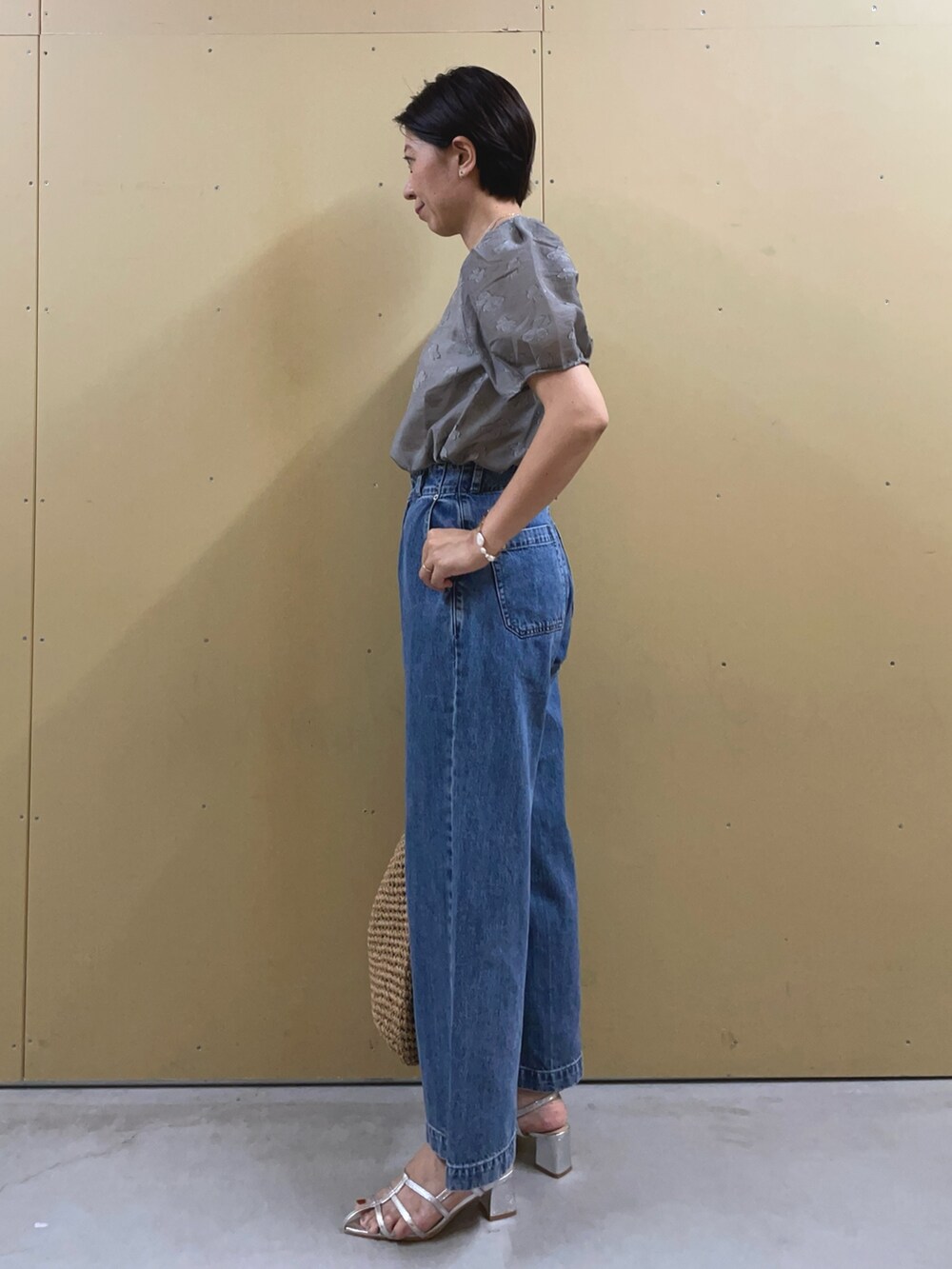 シルバー系のサンダル、ブルー系のデニムパンツ、ブラウン系のかごバッグを着用したレディースの夏コーディネートの3枚目の写真