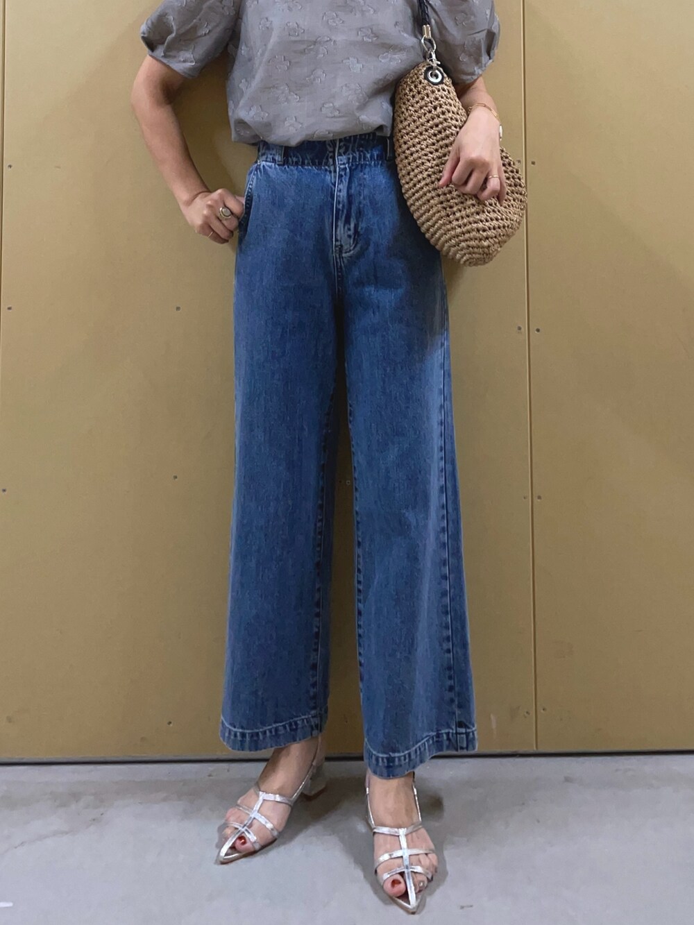 シルバー系のサンダル、ブルー系のデニムパンツ、ブラウン系のかごバッグを着用したレディースの夏コーディネートの6枚目の写真