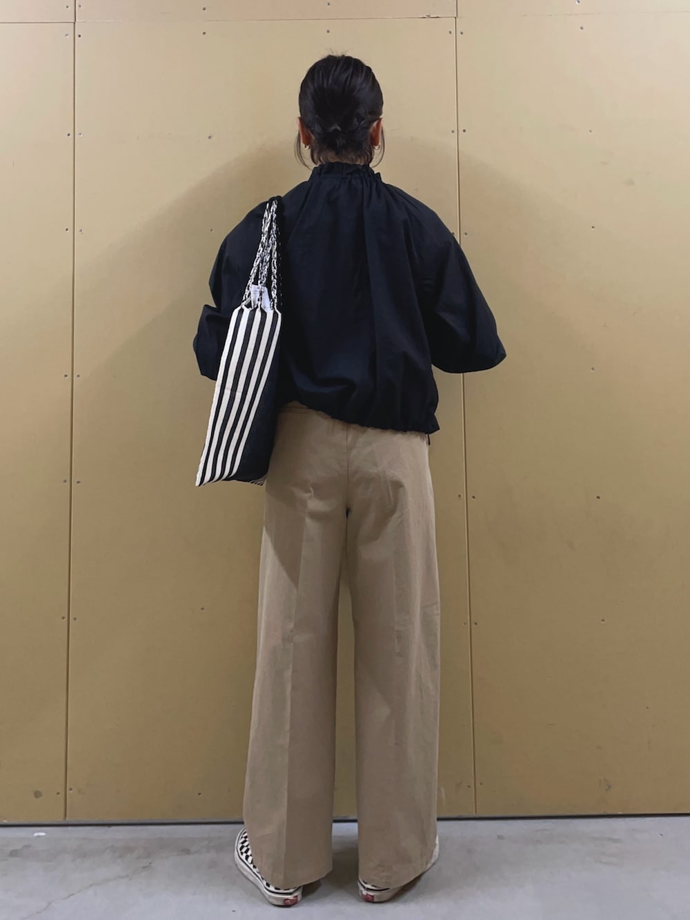 ブラック系のブルゾン、ベージュ系のチノパンツ、ブラック系のトートバッグを着用したレディースの春コーディネートの4枚目の写真