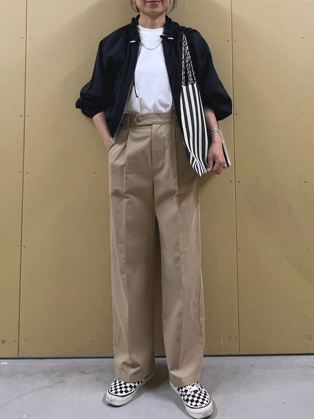 ブラック系のブルゾン、ベージュ系のチノパンツ、ブラック系のトートバッグを着用したレディースの春コーディネートの2枚目の写真