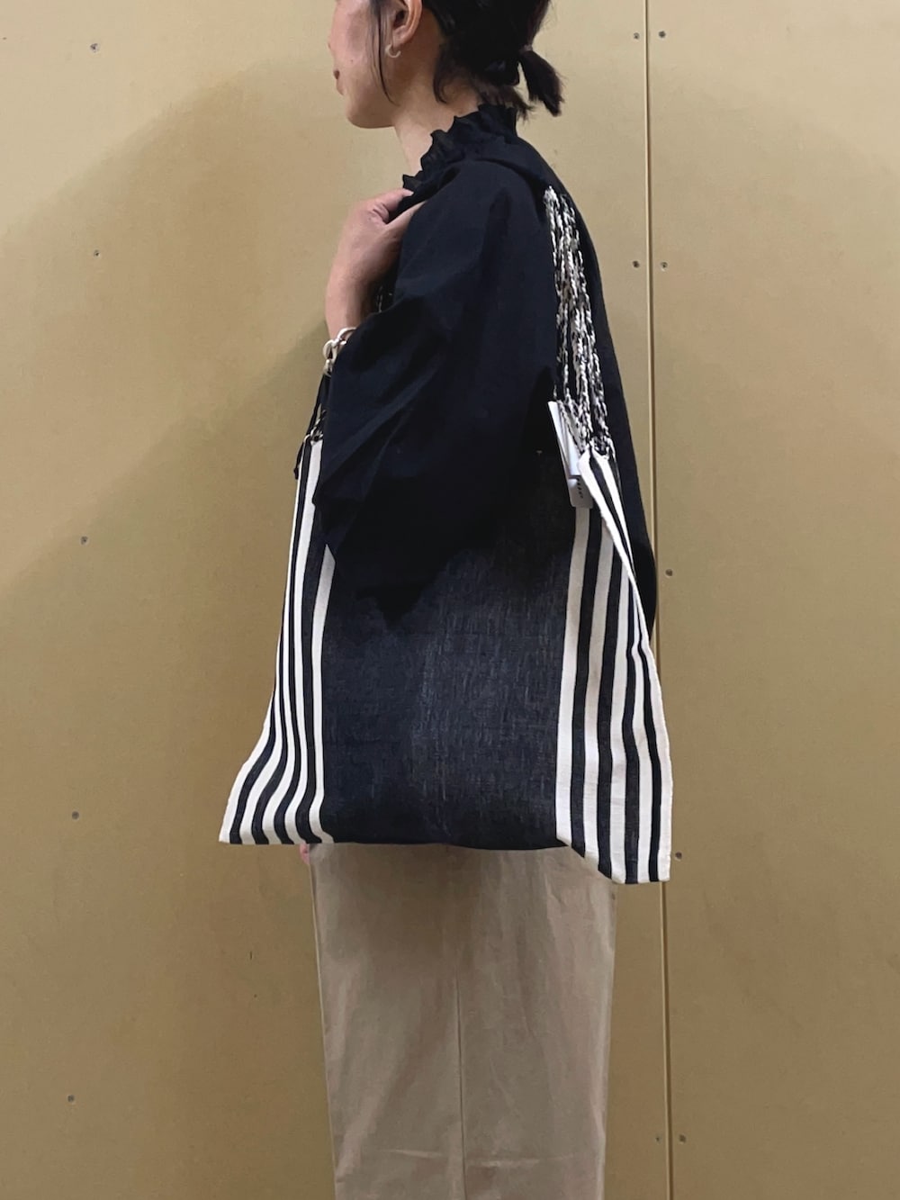 ブラック系のブルゾン、ベージュ系のチノパンツ、ブラック系のトートバッグを着用したレディースの春コーディネートの6枚目の写真