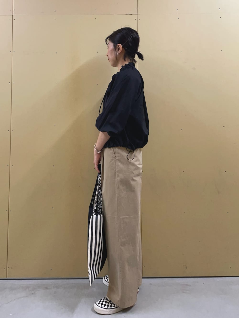 ブラック系のブルゾン、ベージュ系のチノパンツ、ブラック系のトートバッグを着用したレディースの春コーディネートの3枚目の写真