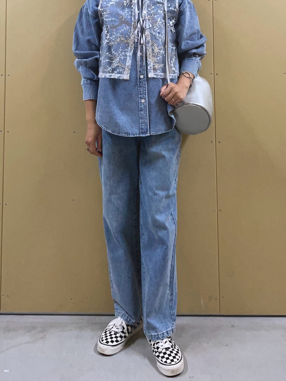 シルバー系のベスト、ブルー系のシャツ/ブラウス、シルバー系のショルダーバッグを着用したレディースの夏コーディネートの2枚目の写真