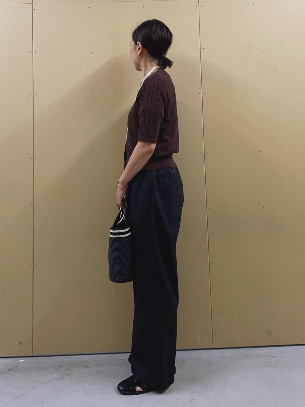 ブラック系のかごバッグ、ブラック系のその他パンツ、ブラウン系のカーディガン/ボレロを着用したレディースの夏コーディネートの3枚目の写真