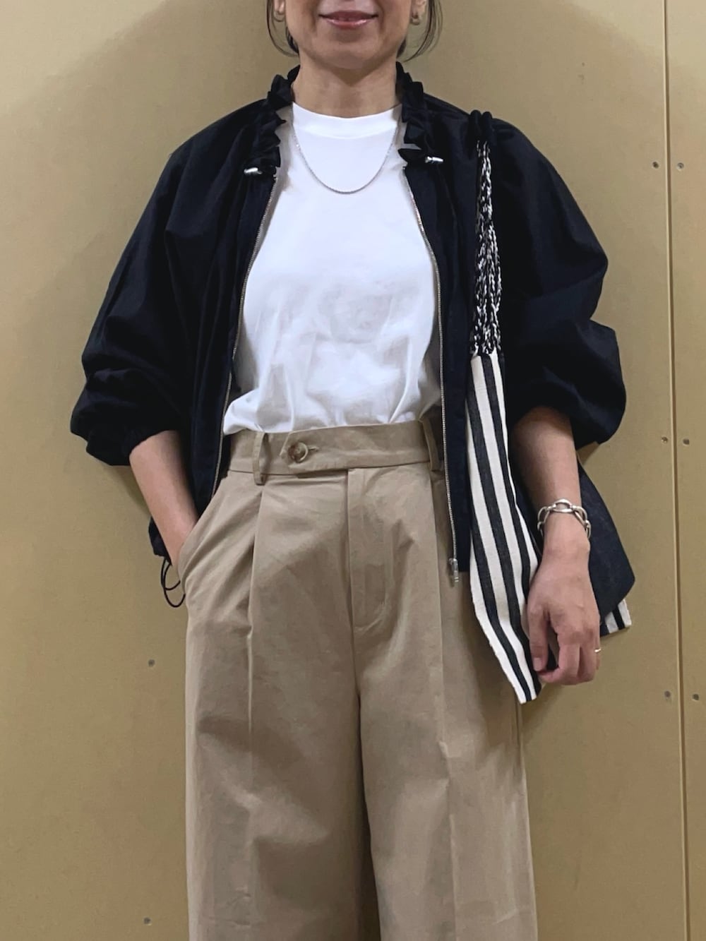 ブラック系のブルゾン、ベージュ系のチノパンツ、ブラック系のトートバッグを着用したレディースの春コーディネートの5枚目の写真