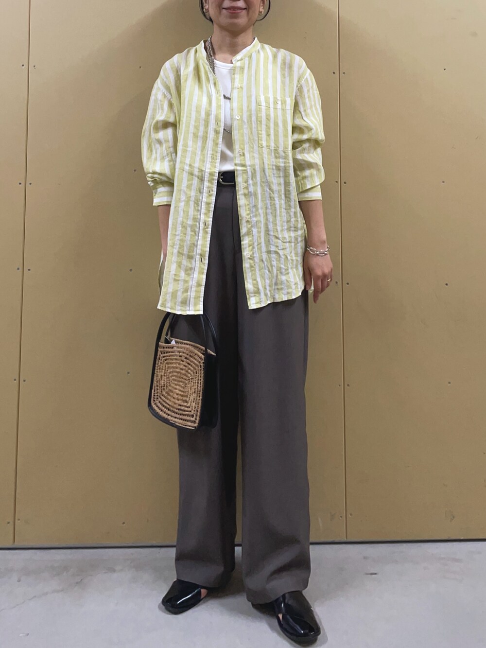 イエロー系のシャツ/ブラウス、ブラック系のサンダル、シルバー系のネックレスを着用したレディースの春コーディネートの2枚目の写真