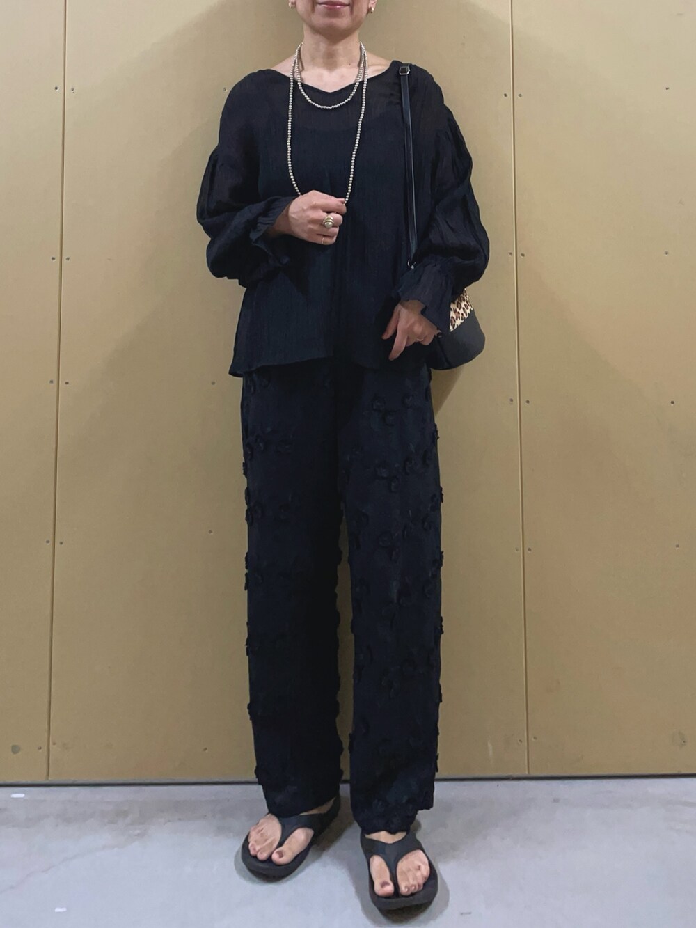 ブラック系のサンダル、ブラック系のその他パンツ、ベージュ系のショルダーバッグを着用したレディースの夏コーディネートの2枚目の写真