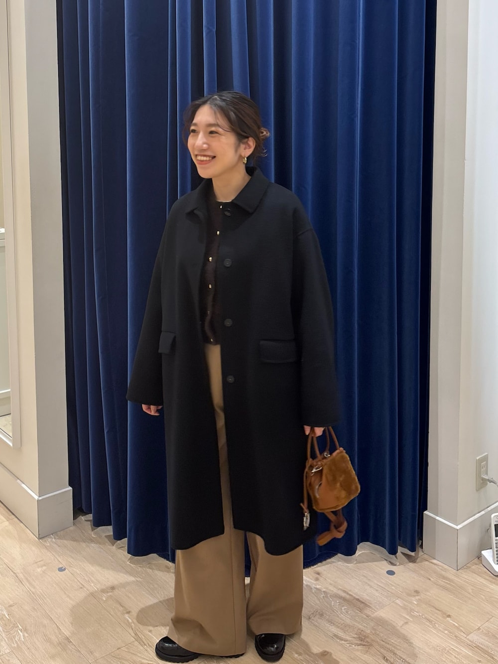 ブラック系のステンカラーコート、ブラウン系のカーディガン/ボレロ、イエロー系のその他パンツを着用したレディースの秋コーディネートの4枚目の写真