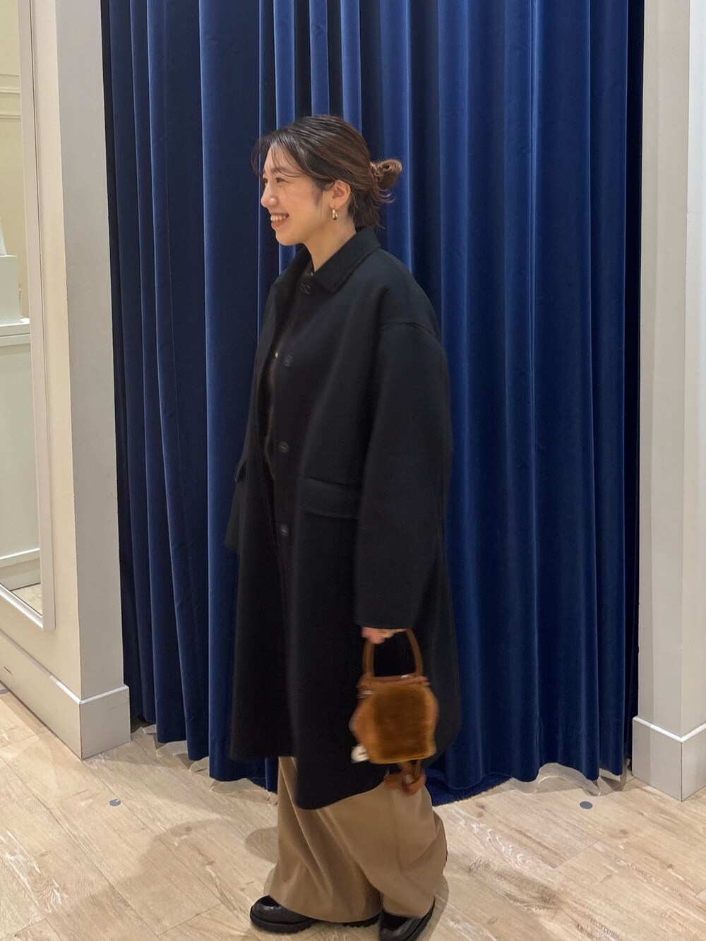 ブラック系のステンカラーコート、ブラウン系のカーディガン/ボレロ、イエロー系のその他パンツを着用したレディースの秋コーディネートの5枚目の写真