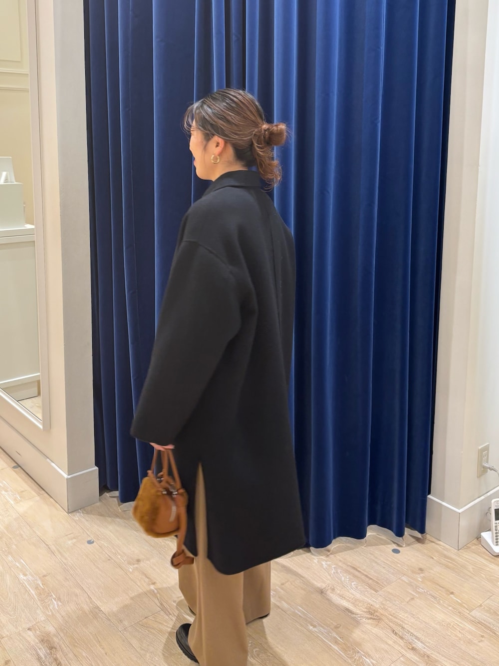 ブラック系のステンカラーコート、ブラウン系のカーディガン/ボレロ、イエロー系のその他パンツを着用したレディースの秋コーディネートの6枚目の写真