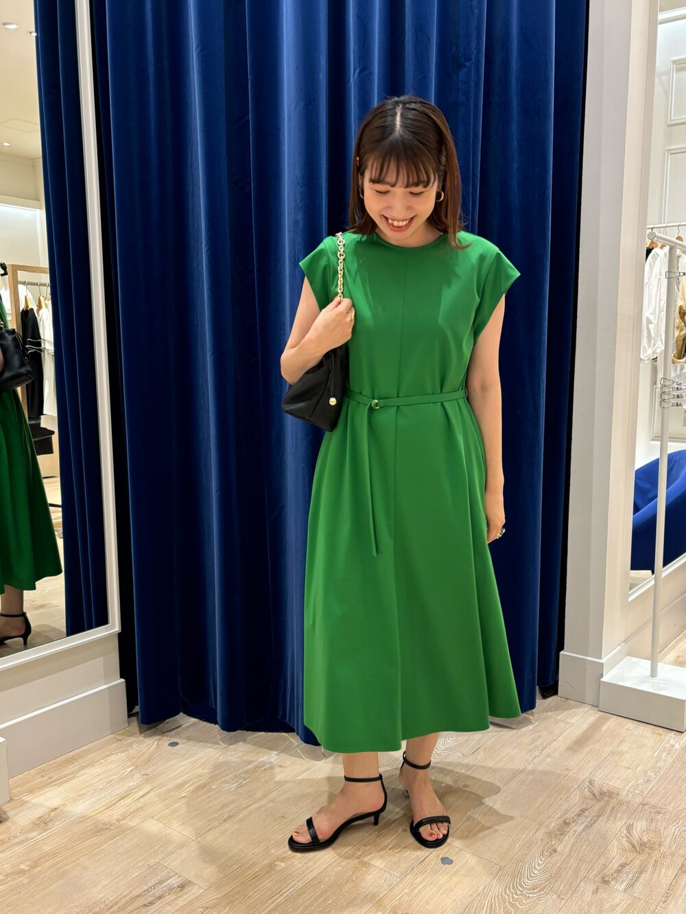 グリーン系のワンピース、ブラック系のショルダーバッグ、ブラック系のサンダルを着用したレディースの夏コーディネートの2枚目の写真