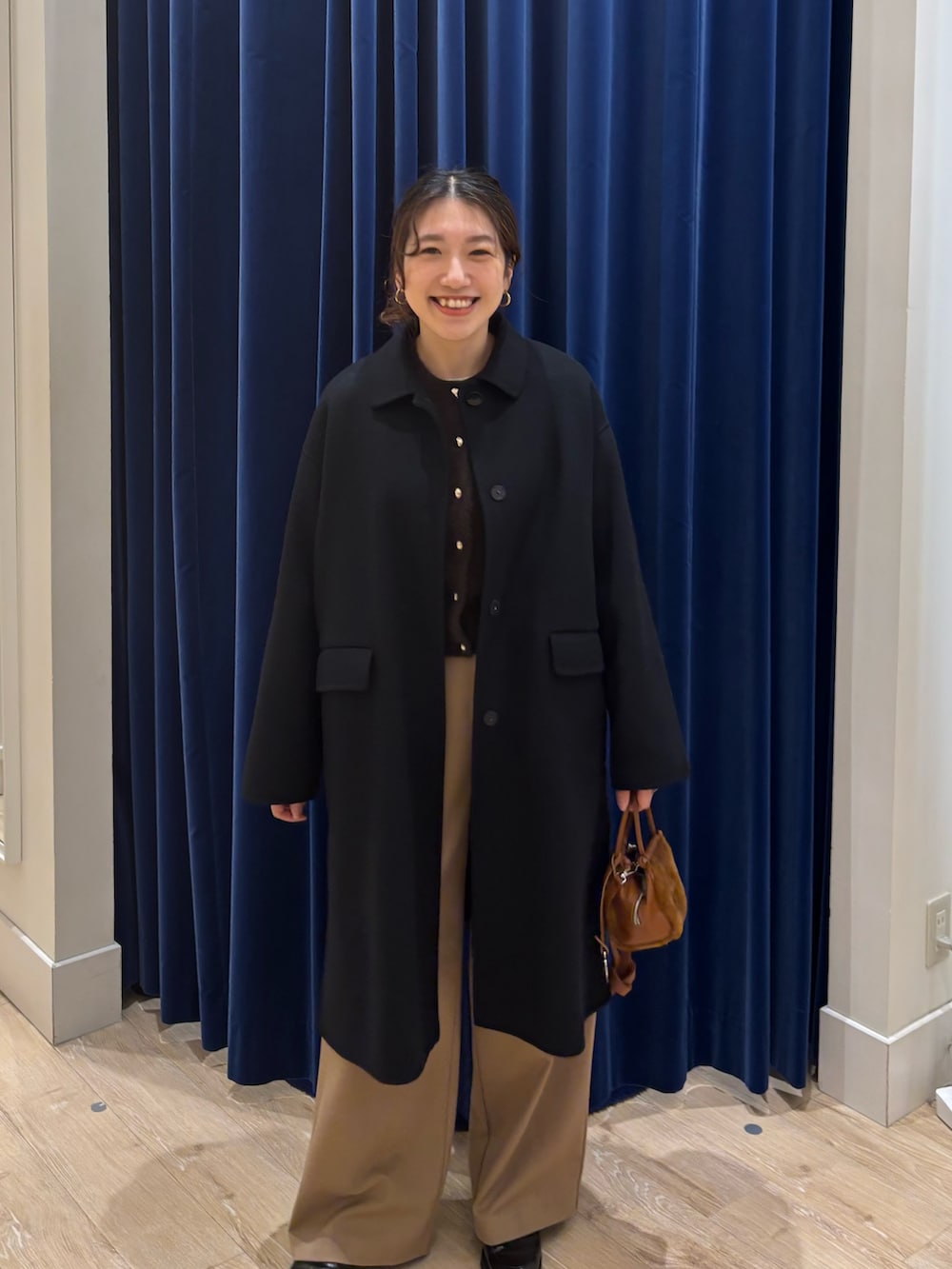 ブラック系のステンカラーコート、ブラウン系のカーディガン/ボレロ、イエロー系のその他パンツを着用したレディースの秋コーディネートの3枚目の写真