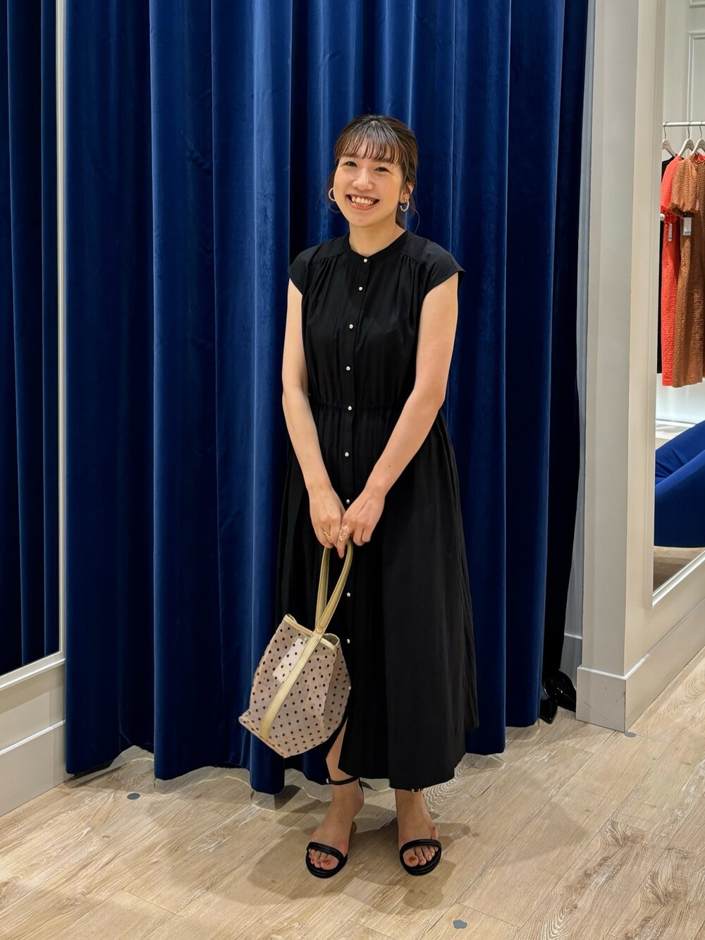 ブラック系のワンピース、ベージュ系のトートバッグ、ブラック系のサンダルを着用したレディースの春コーディネートの2枚目の写真