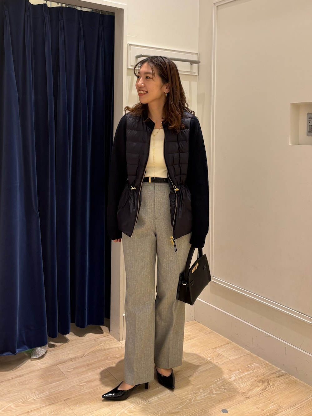 グレー系のその他パンツ、ブラック系のショルダーバッグ、ホワイト系のニット/セーターを着用したレディースの秋コーディネートの3枚目の写真