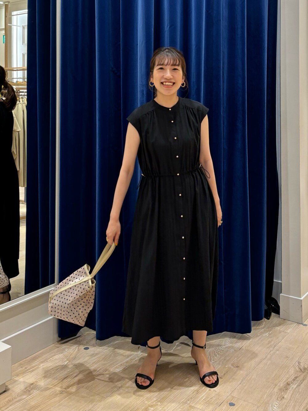 ブラック系のワンピース、ベージュ系のトートバッグ、ブラック系のサンダルを着用したレディースの春コーディネートの4枚目の写真